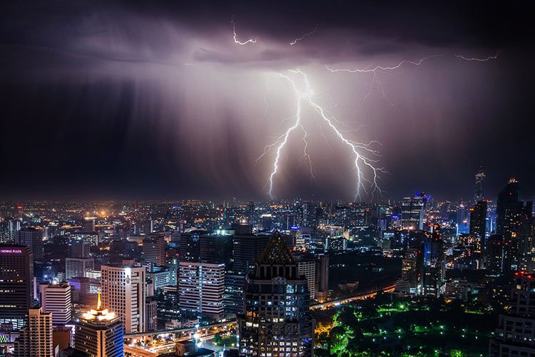 A powerful lightning strikes just above the city in the midst of a big thunderstorm