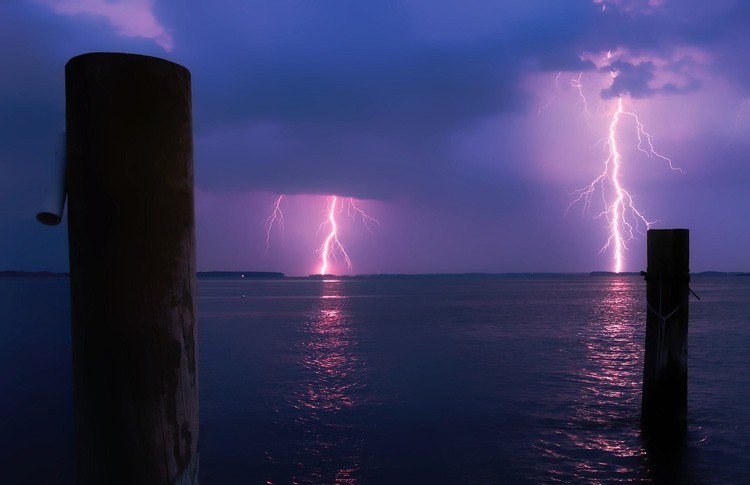 A purple lightning bolts strikes on the horizon and being photographed by Smart+
