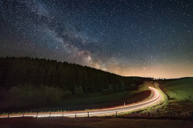 milky way and moving cars at night