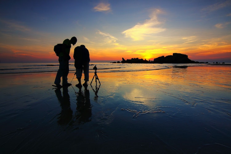 Photographers setting their tripods to take long exposure photographs at sunset