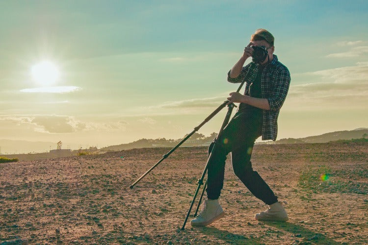 A photographer capturing a photo with DSLR and the tripod on his hands