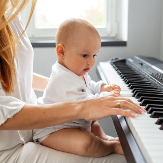 Mom playing music on a piano to her baby