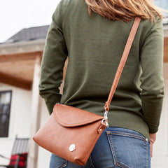 Back of woman with the Momkindness small brown leather clutch purse over her shoulder.