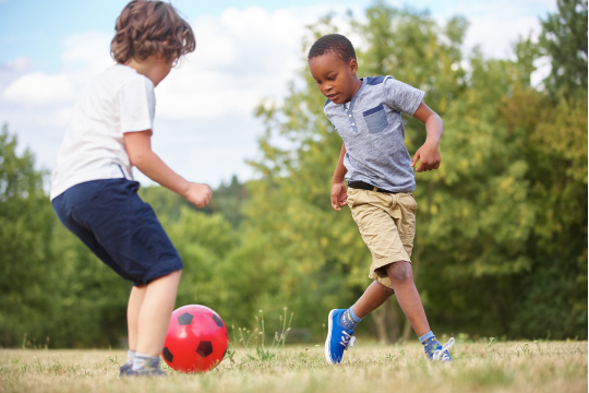 Two boys playing soccer in a field