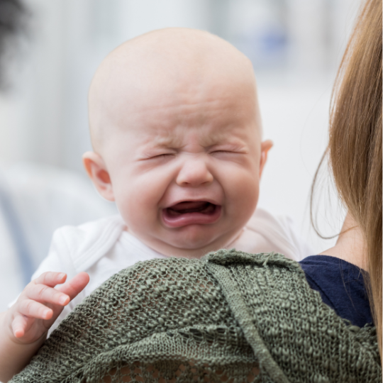 Baby crying in parent's arms as part of a guide to understanding baby's needs