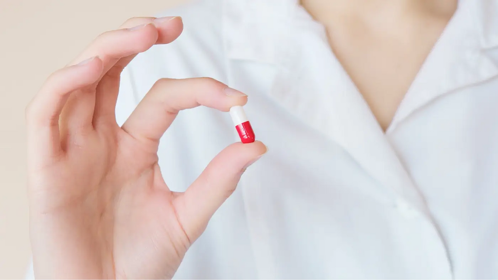 zoom on a woman's hand holding a white and red capsule