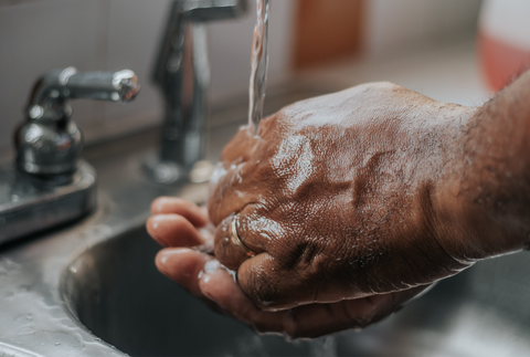 Menscht wäscht sich die Hände mit Seife unter dem Wasser