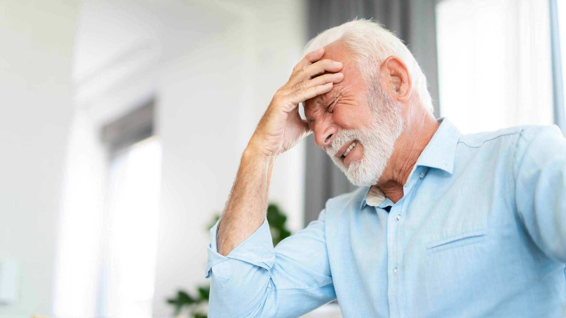 old man with headache holding his head