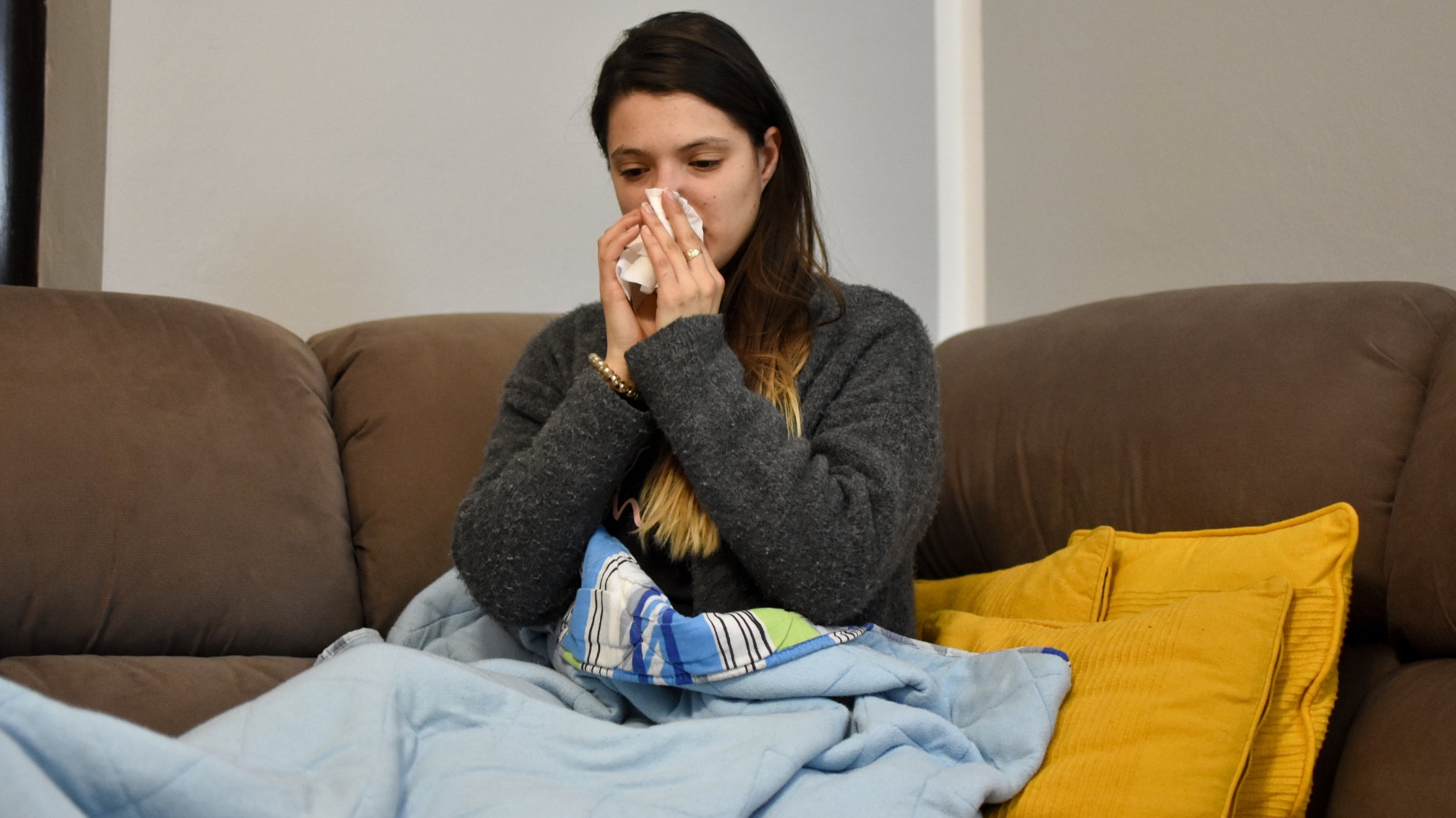 woman with covid wiping nose with tissue