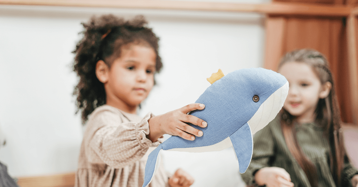 Girl holding up stuffed animal whale