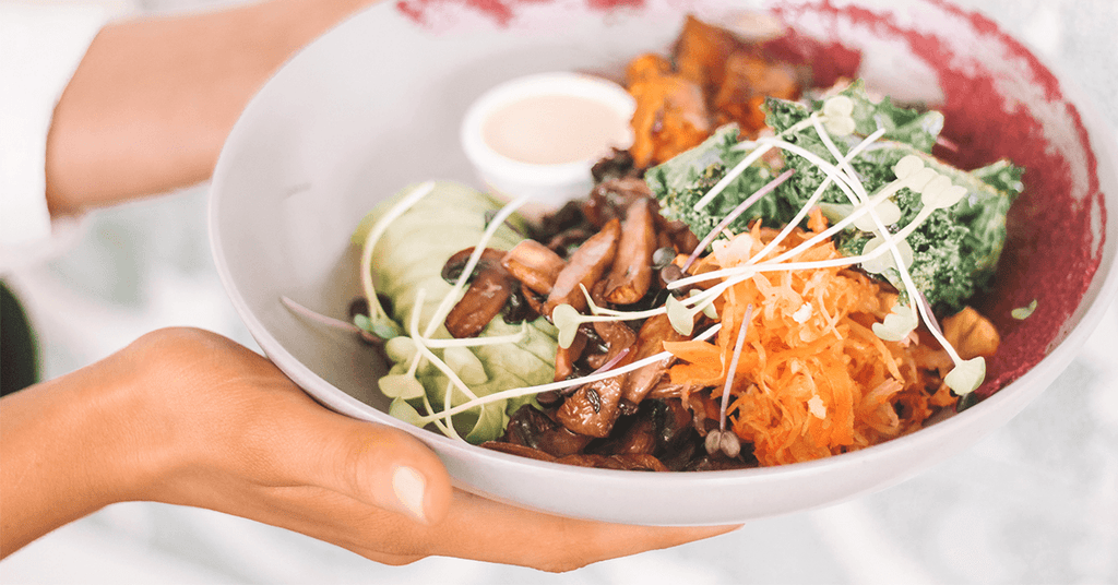 Holding plant-based protein bowl filled with veggies 