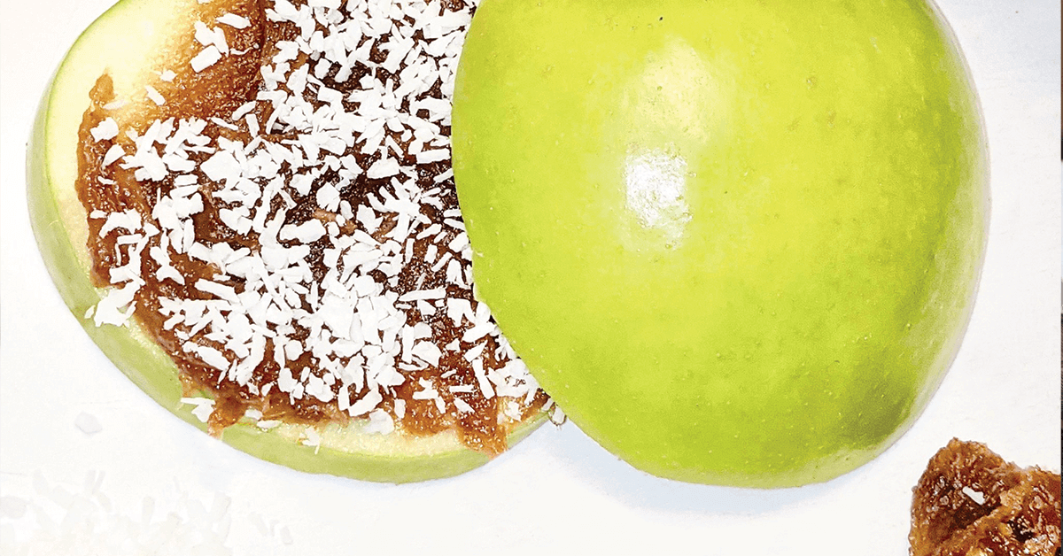 Sliced apple with a date sauce spread on top, sprinkled with coconut bits
