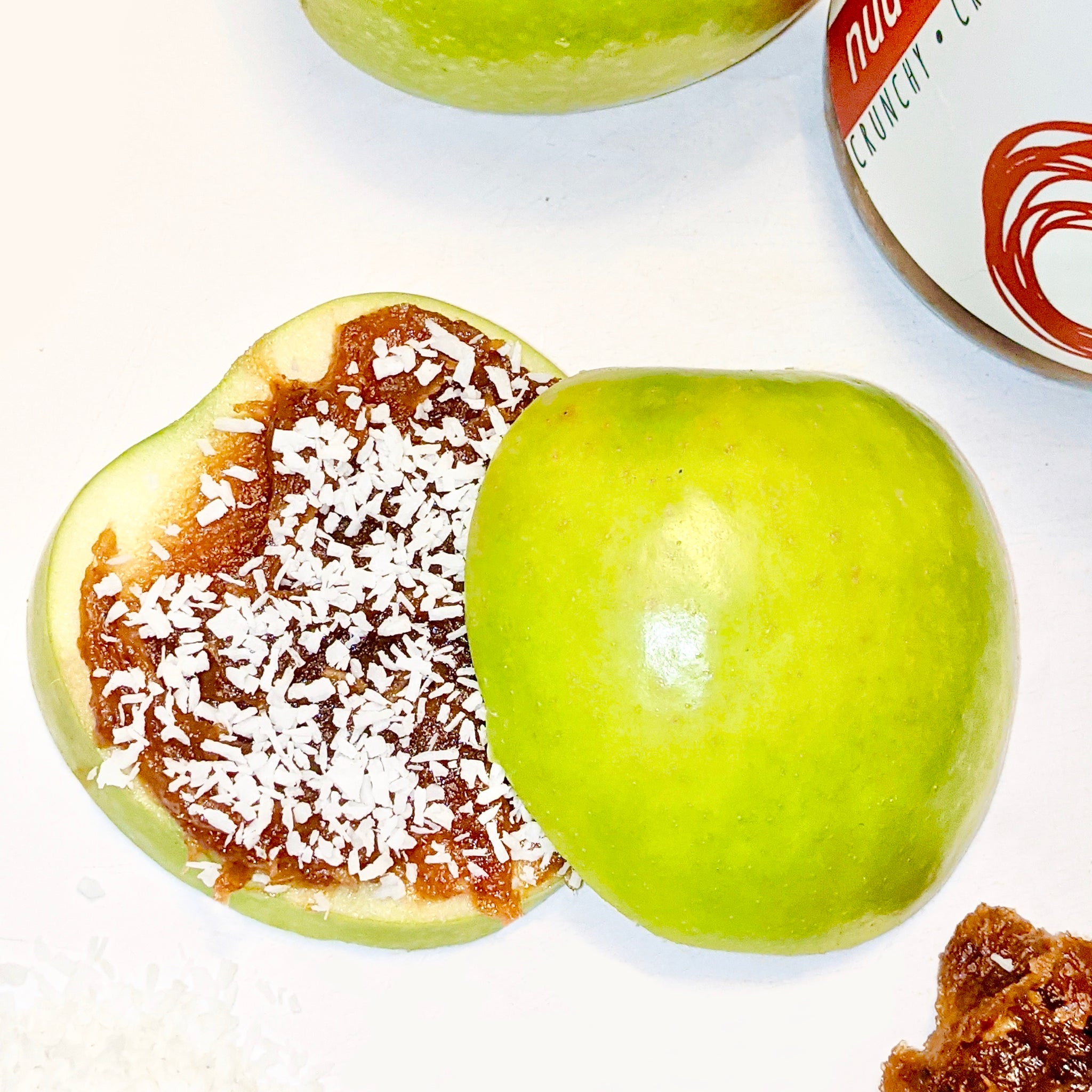 Sliced apple with natural peanut butter caramel date sauce spread, sprinkled with coconut shavings on top. 
