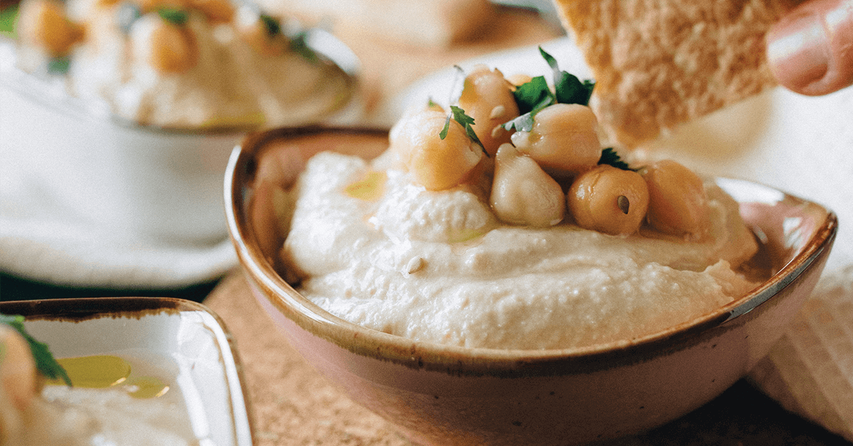 Cracker dipping in bowl of hummus