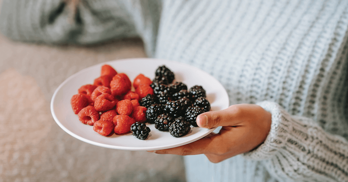 Women holding plate of raspberries and blackberries