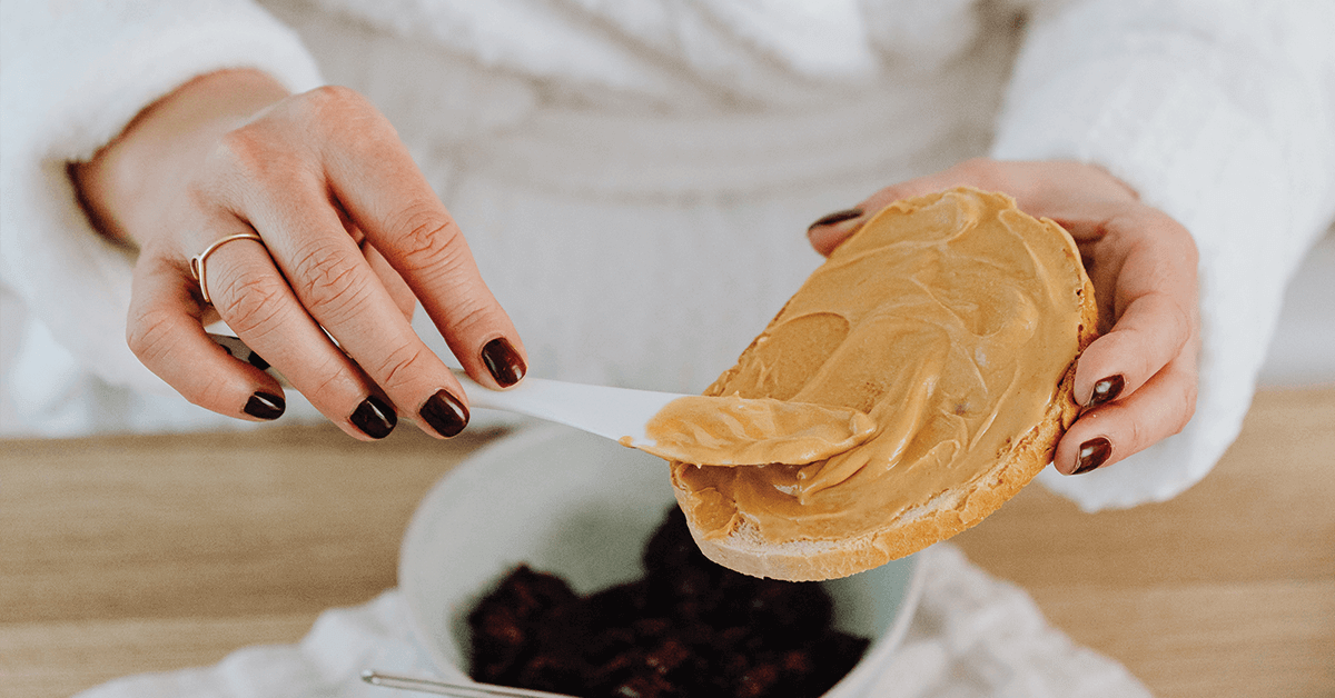 Hands spreading peanut butter on a piece of bread