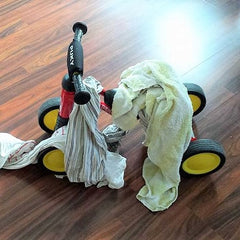 Kleinkind hilft beim Wäsche aufhängen und hängt Wäsche auf seinem Rutschfahrzeug auf
