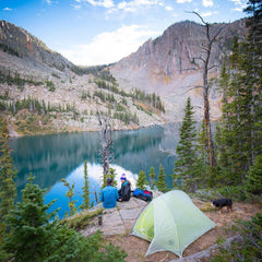 two friends are camping on bank of river