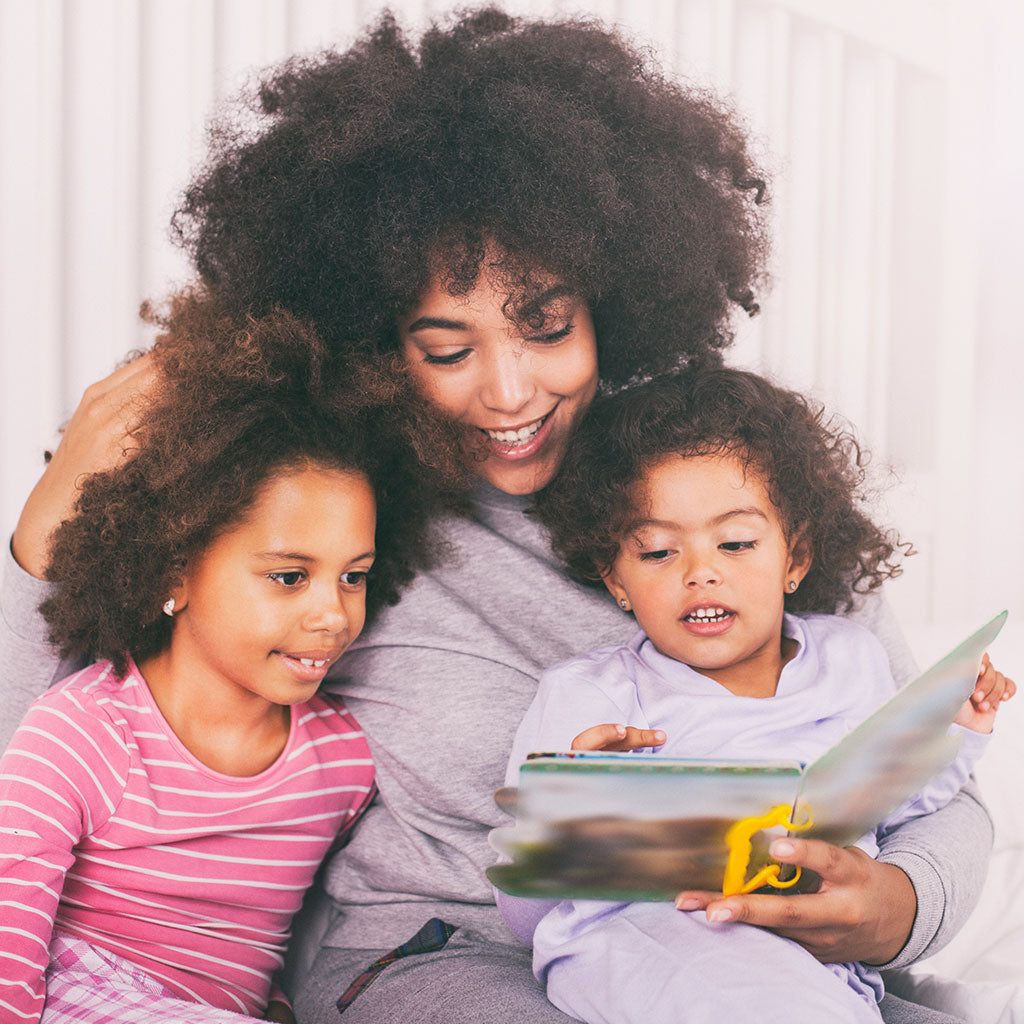 Mother reading a book to her two kids