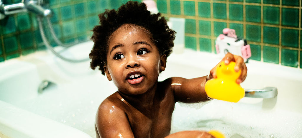 Boy in bath holding a yellow rubber duck