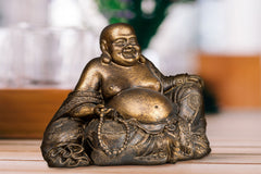 Bouddha rieur cuivré posé sur une table en bois Kaosix