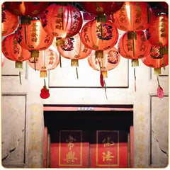 Des lampes chinoises en papier suspendues au dessus d'une porte chinoise dans une rue Kaosix