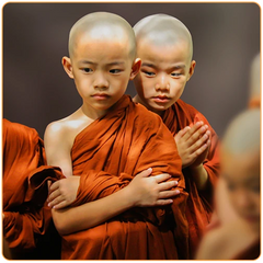 Deux enfants moines tibétains en tunique orange debouts de face et qui regardent quelque chose par terre kaosix