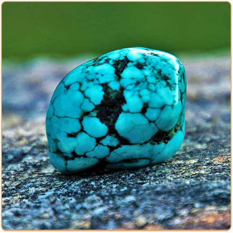 Gros galet de pierre turquoise posé sur un rocher gris Kaosix