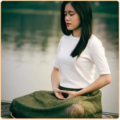 Jeune femme asiatique en position du lotus les yeux fermés sur un ponton en bois au bord d'un lac Kaosix