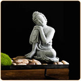 Statue Bouddha assis penseur posé sur des galets de pierre avec fond noir Kaosix