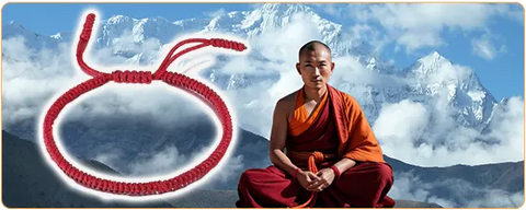 Un_moine_tibetain_en_position_du_lotus_avec_des_montagne_enneigees_en_arriere_plan_et_un_bracelet_rouge_tresse_tibetain_en_gros_plan_a_cote_de_lui_kaosix