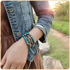 Une femme dans la campagne portant une veste en jeans, une robe marron et portant un bracelet wrap en pierres naturelles au poignet gauche Kaosix