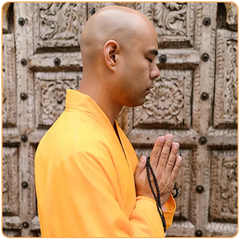 Un moine bouddhiste en robe couleur safran en train de prier avec le geste de salutation Namaste kaosix