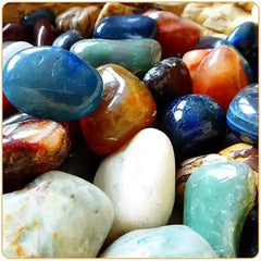 groupe de galets polis de differentes pierres amassées les une sur les autres avec un galet de lapis lazuli sur le sommet Kaosix