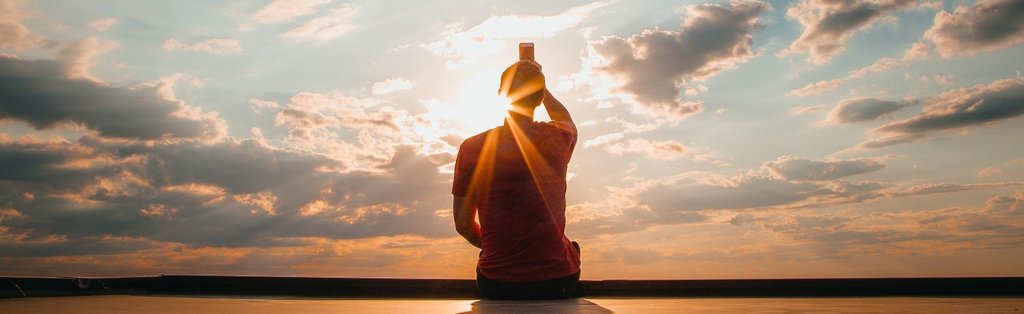 une personne en meditation assis devant un coucher de soleil Kaosix