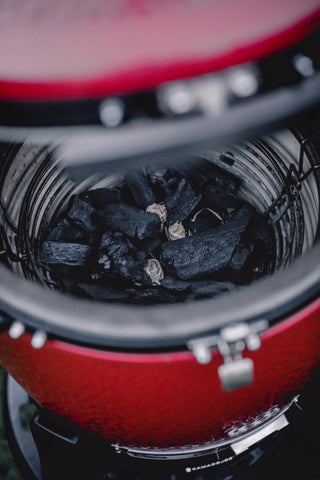 A pile of big block XL charcoal sites in the basket of an open Kamado Joe grill with not cooking grates installed