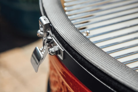 Close-up of the stainless steel latch and wire mesh gasket on the base of a Kamado Joe grill