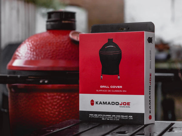 The box for a Kamado Joe grill covers sits in front of a Kamado Joe grill