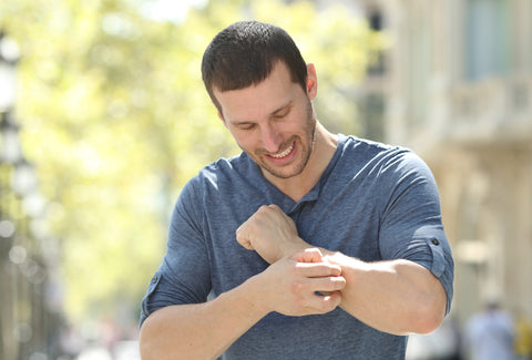 the image shows a man scratching his arm