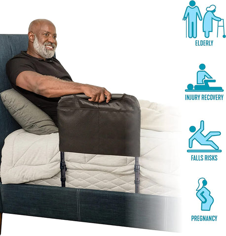 A man is lying in a bed – he rests his back against a headboard. His right arm rests on the Beside Safety Rail for Support