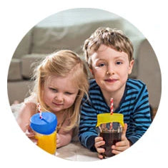 Two children using Safe Sips on top of two glasses