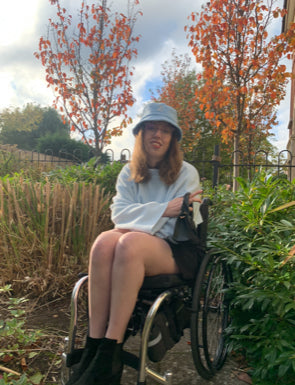 Emily Mancock sitting in a wheelchair in a countryside setting