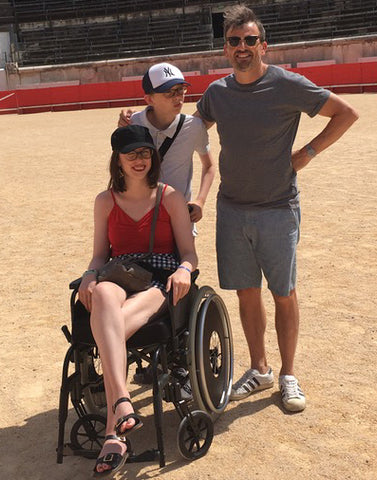 Emily Manock is her wheelchair with two friends/family in the background