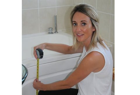 Kate measuring the height of a bath with a tape measure