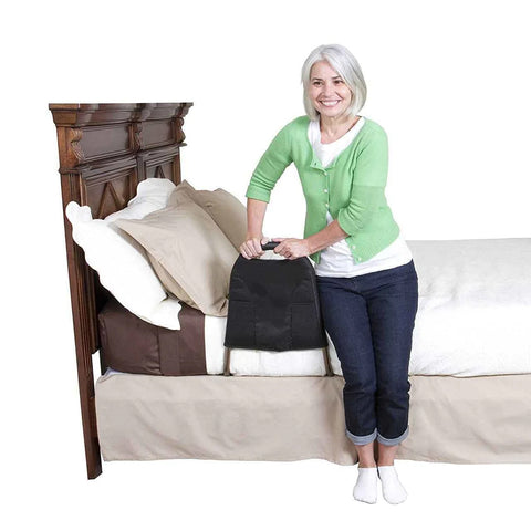 A woman stands next to a bed - she is smiling and is leaning on the Mighty Rail for support