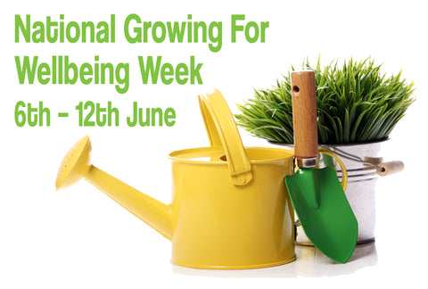 A yellow watering can on a white background is in front of a white pot containing a grassy-looking plant. There is a small green spade leaning against the watering can. The words – National Growing For Wellbeing Week, 6th-12th June – can also be seen