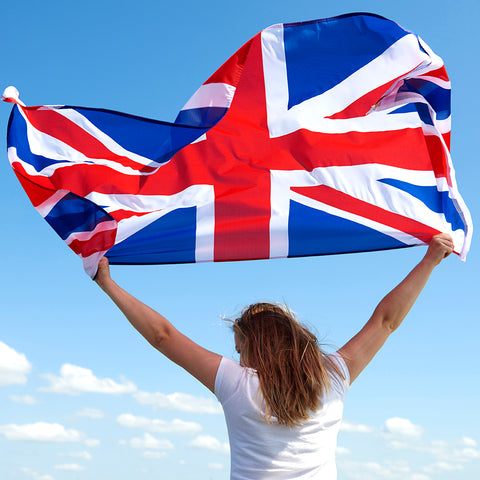 The backview of a woman - she is holding the British flag which is flapping wildly in the wind