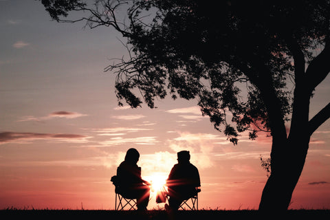 An image of two people sat in front of a sunset