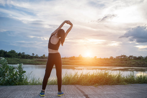 An image of a woman stretching infront of a sunset