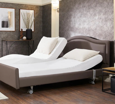 The Opera Signature Comfort Dual Profiling Bed. One side of the mattress platform backrest has been raised higher than the other to show profiling bed independence. The handheld control hangs near the top of the profiling bed.